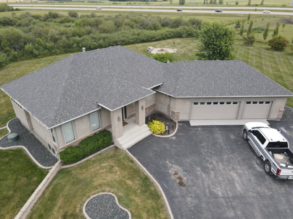 Drone view of a completed grey shingle roof on a rural acreage bungalow near Winnipeg — Trudel Roofing