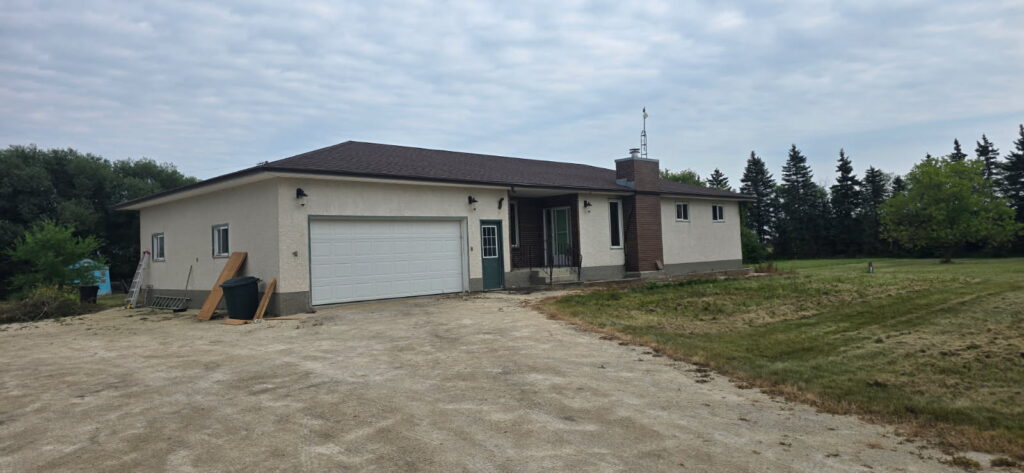 Rural stucco bungalow with a new brown shingle roof near Winnipeg — Trudel Roofing
